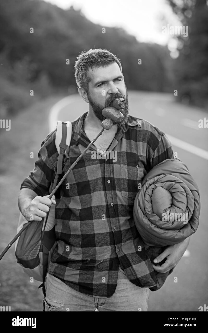 Hitchhiker walking next to highway. Bearded man with rucksack, sleeping