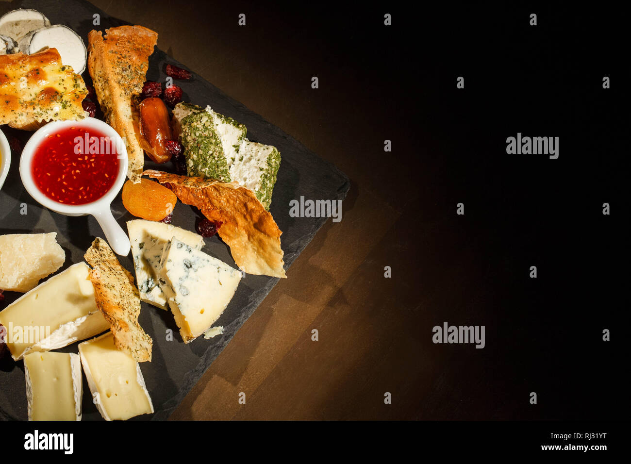 Look from above at black dish with blue cheese, camembert, brie and sauces Stock Photo