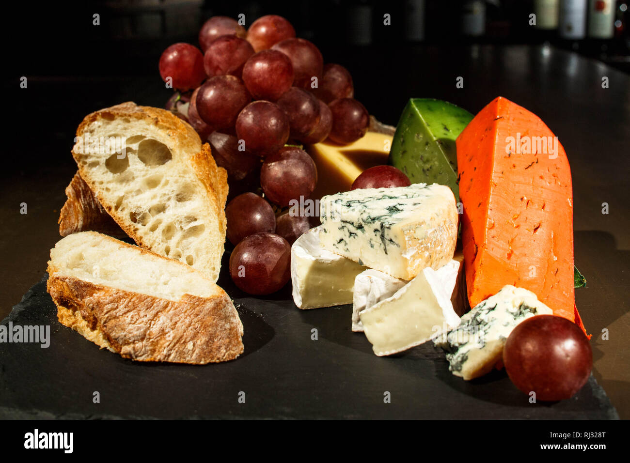 Pieces of cheese and bread on black dish Stock Photo