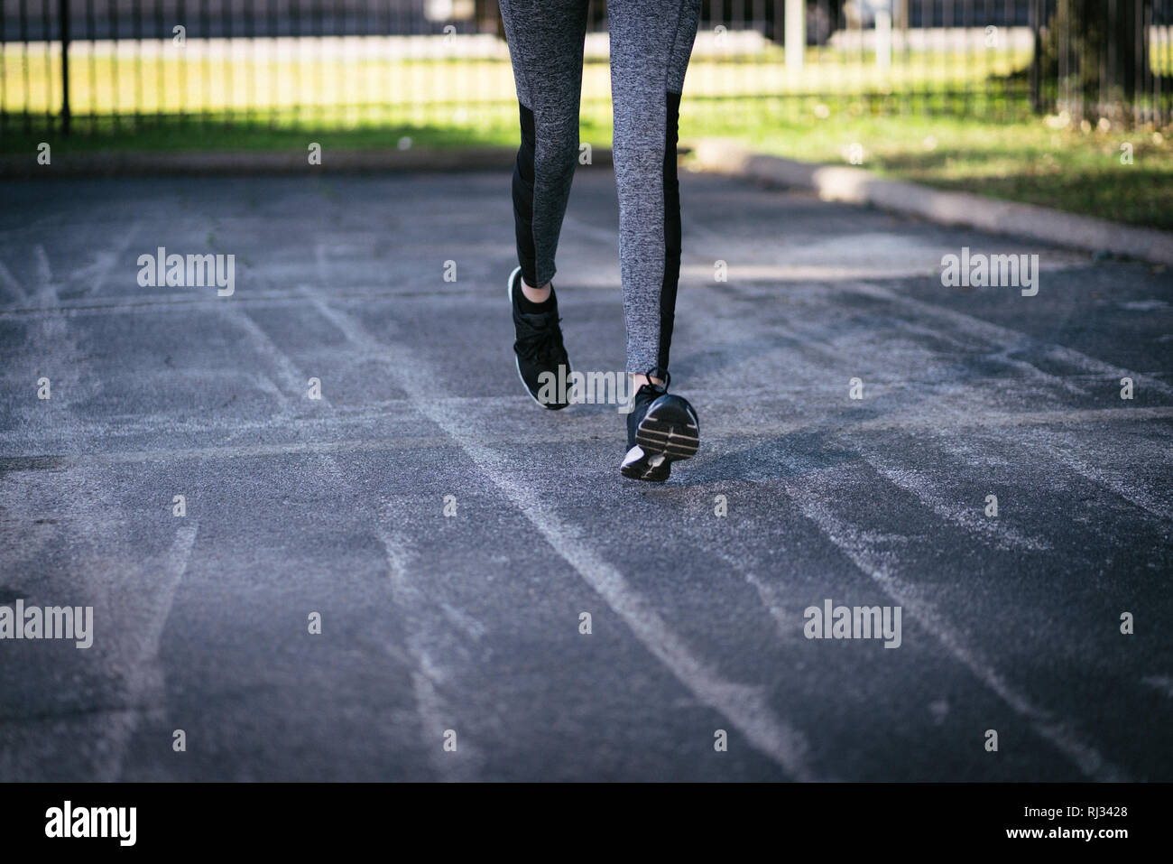 Woman's legs jogging on concrete parking lot or sidewalk for fitness exercise Stock Photo