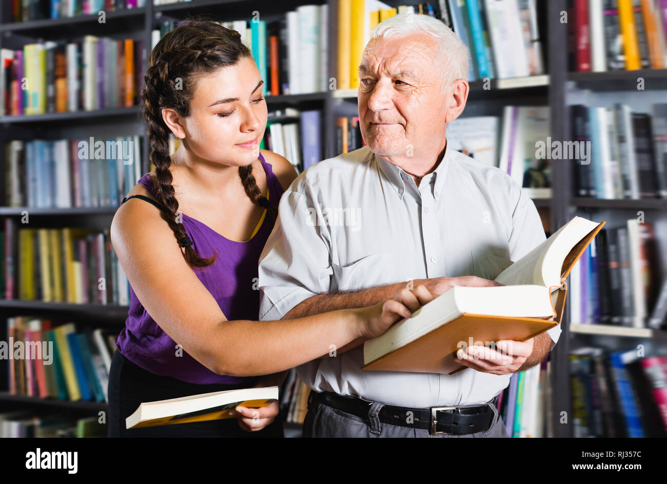 Old man with adult girl are reading books in bookstore Stock Photo Alamy