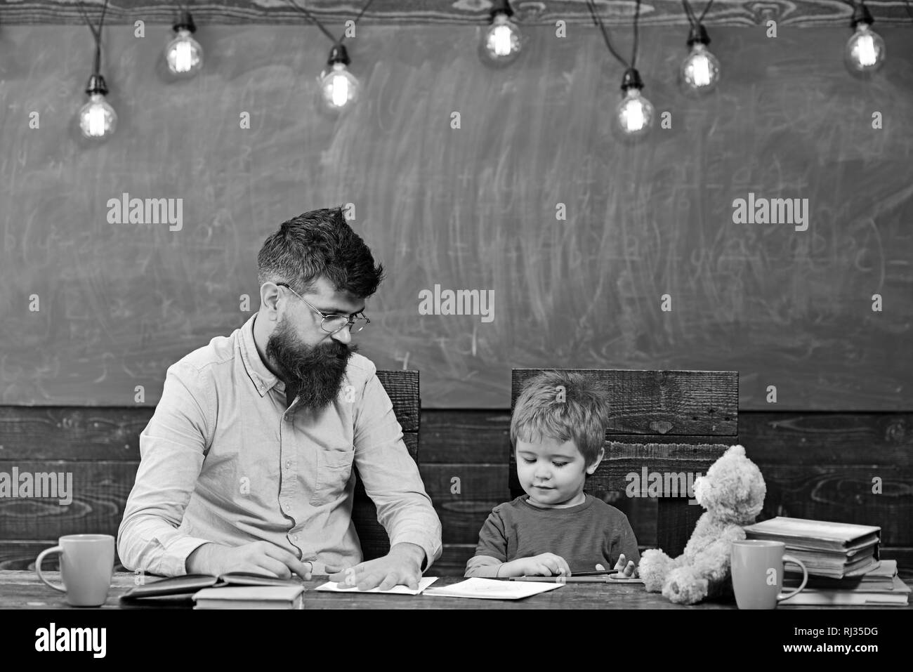Teacher and small kid drawing together. Male teacher showing boy how to ...
