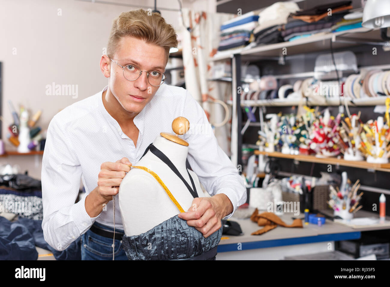 Male fashion designer at work - taking measurements of dummy for ...