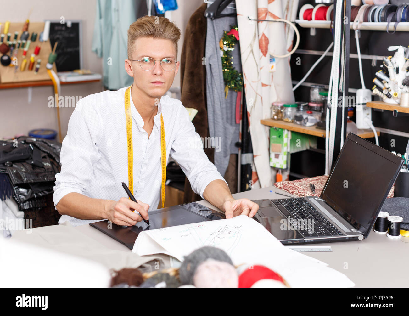 Young male tailor creating  pattern using graphics tablet at sewing atelier Stock Photo