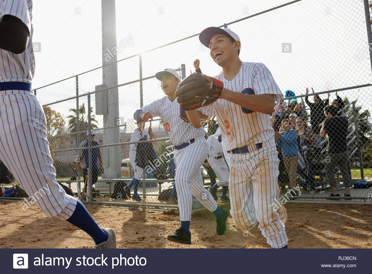 Excited baseball players running onto field Stock Photo