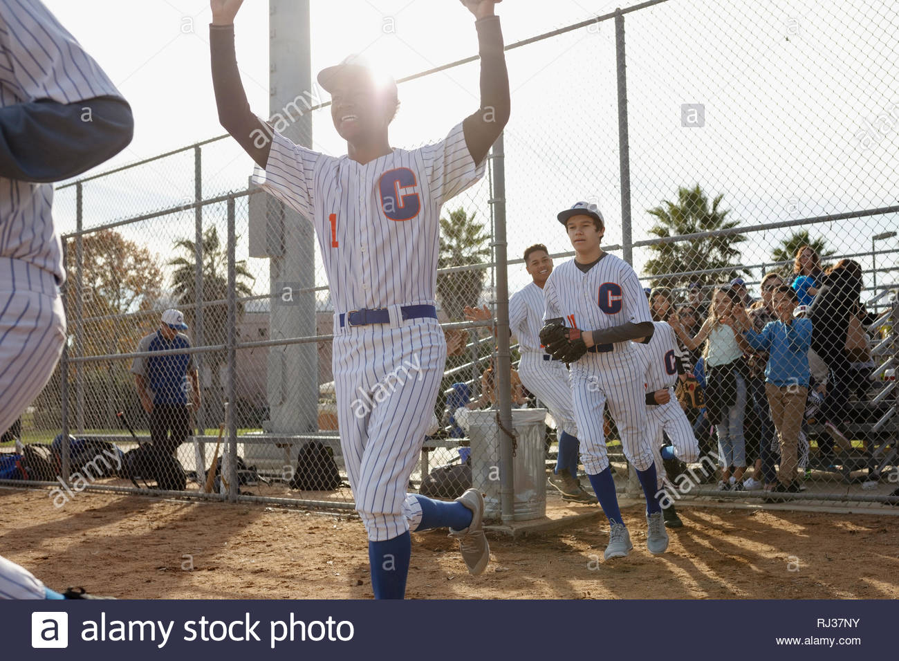 Baseball players running onto sunny field Stock Photo Alamy
