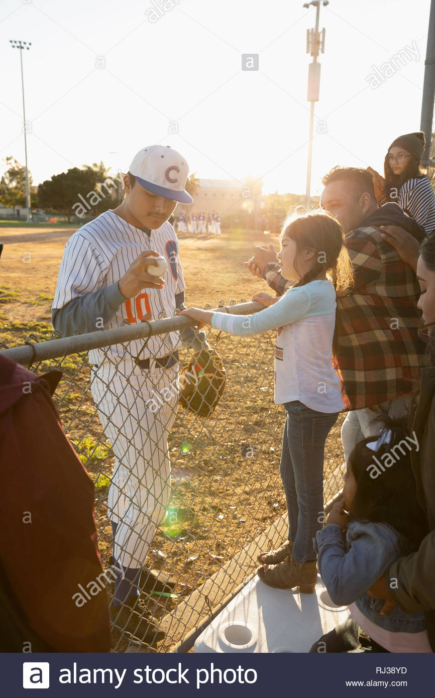 Baseball player showing baseball to girl at fence Stock Photo