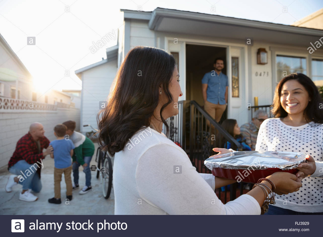 Latinx woman delivering casserole to neighbor Stock Photo