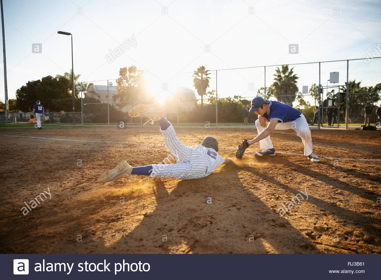 Baseball player sliding into first base on sunny field Stock Photo Alamy