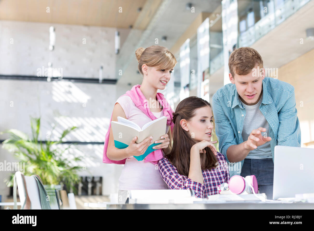 Young students discussing over laptop while making assignment at table in university Stock Photo