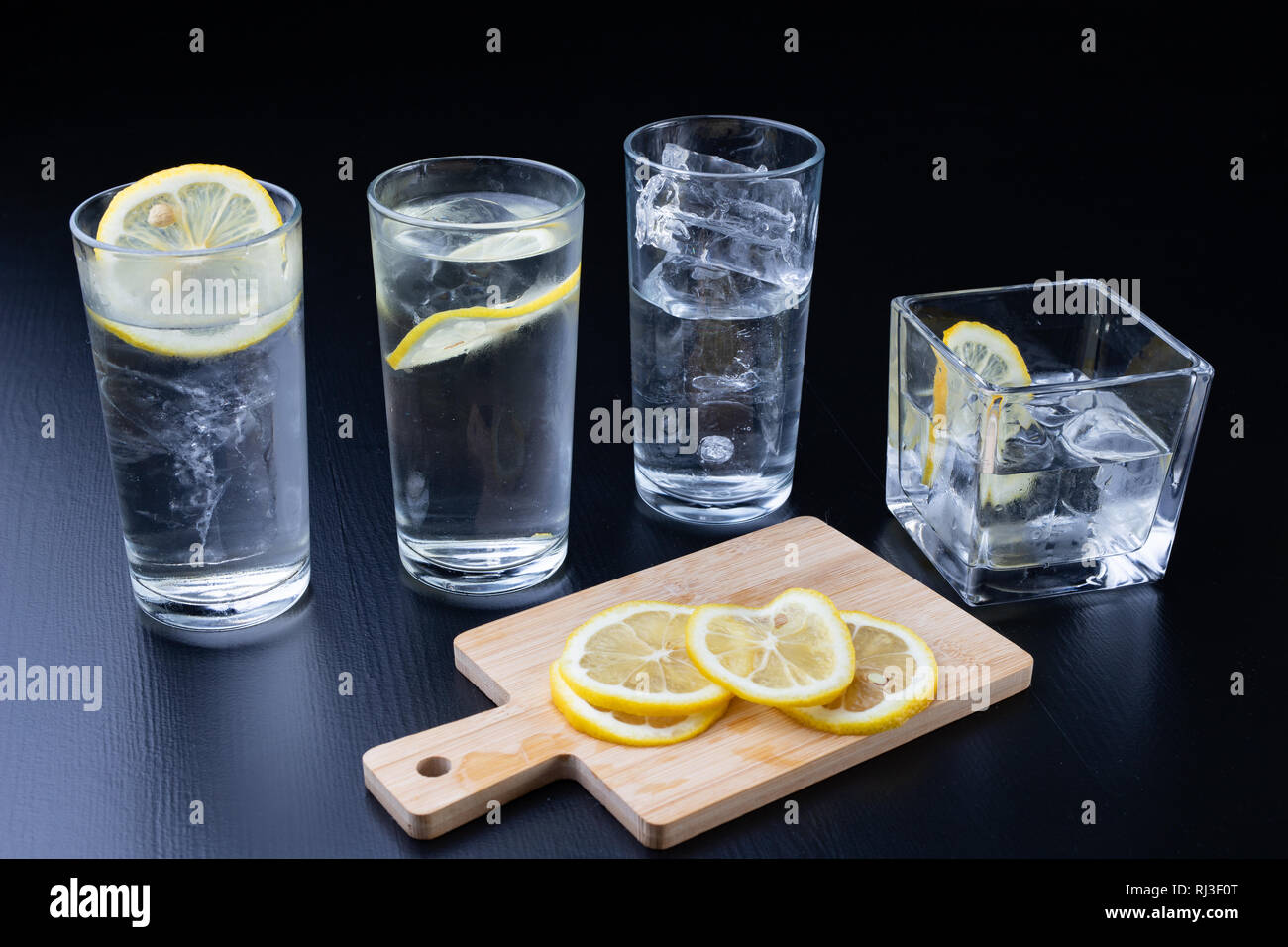 Cold drink in a glass on the kitchen table. Lemon and ice with water ...