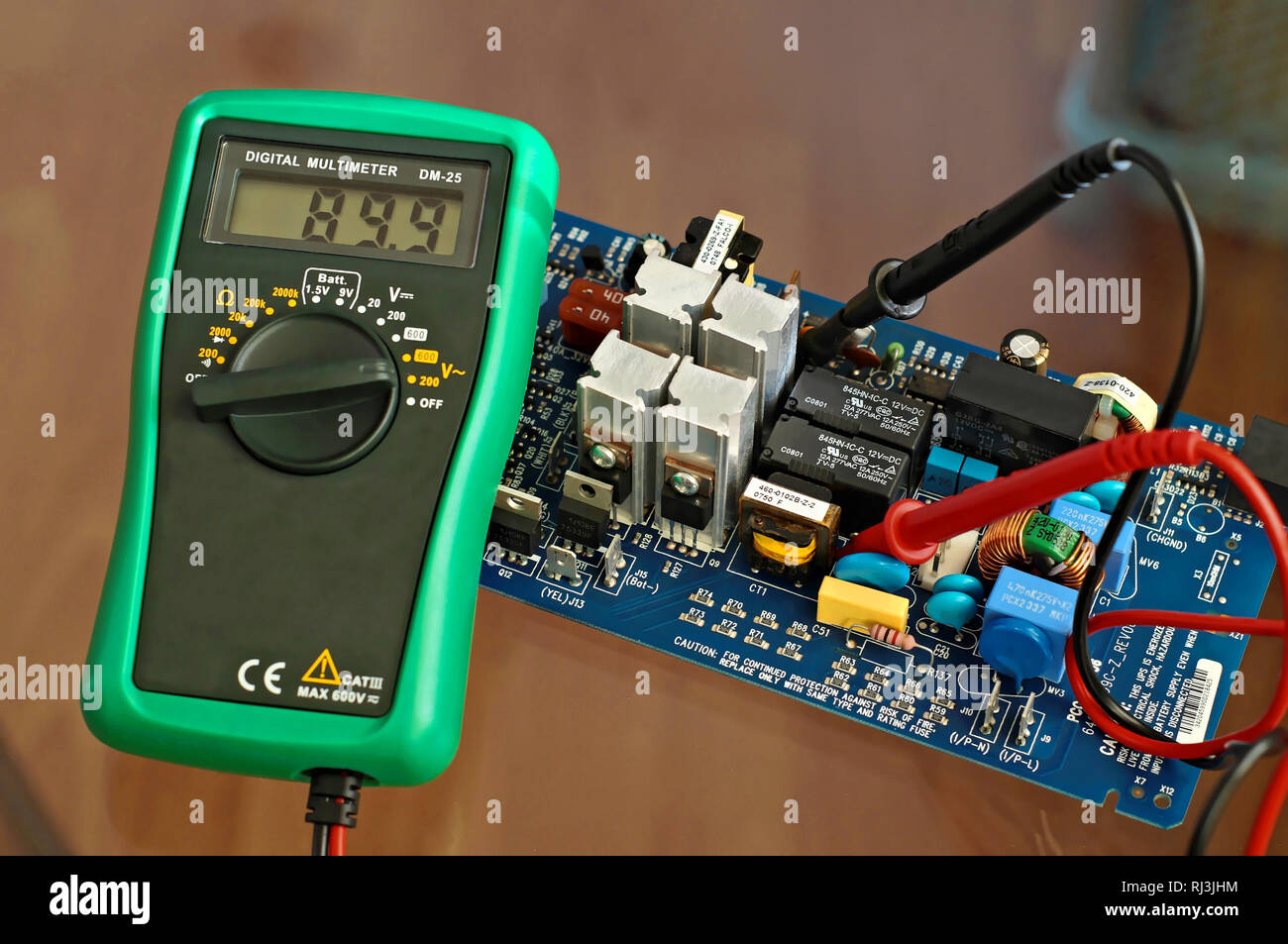 Electronic metering device multimeter showing the voltage parameter in an electronic device consisted of microchip transistor capacitor transformer Stock Photo