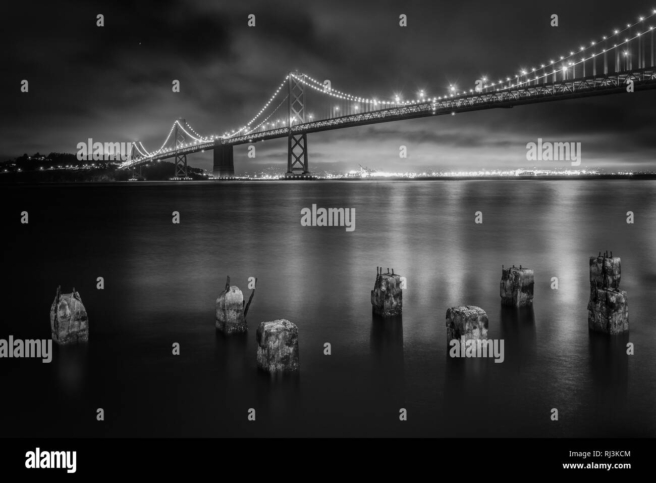 Pier pilings and the San Francisco Oakland Bay Bridge at night, in