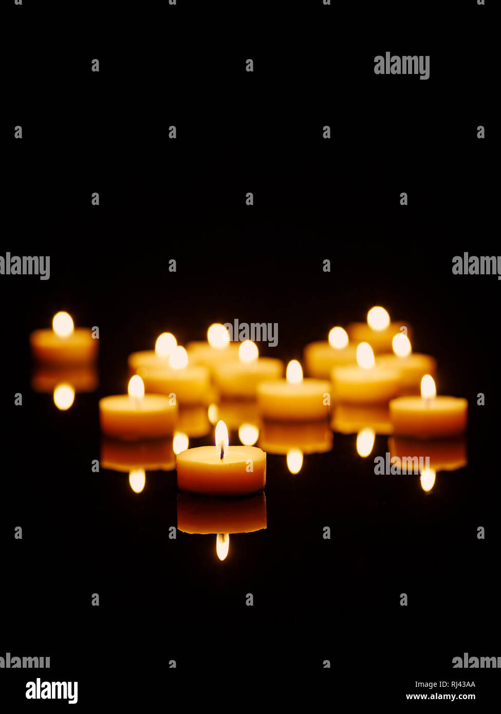 Kerzen mit Spiegelung angez?ndet auf einem schwarzen Tisch Stock Photo