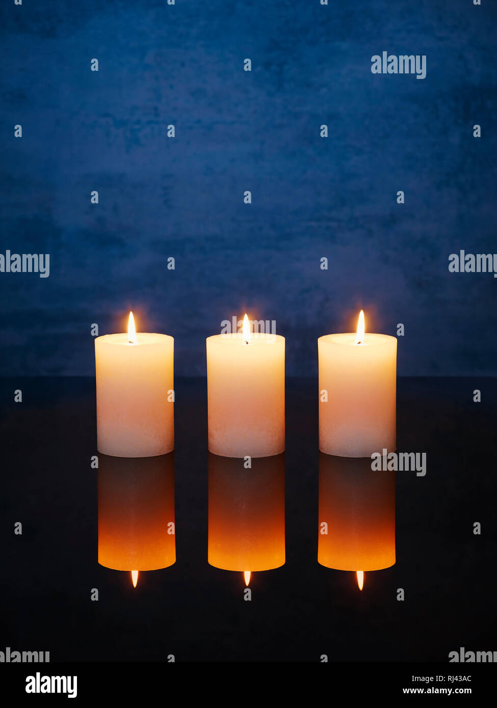 Kerzen mit Spiegelung angez?ndet auf einem Tisch nebeneinander Stock Photo