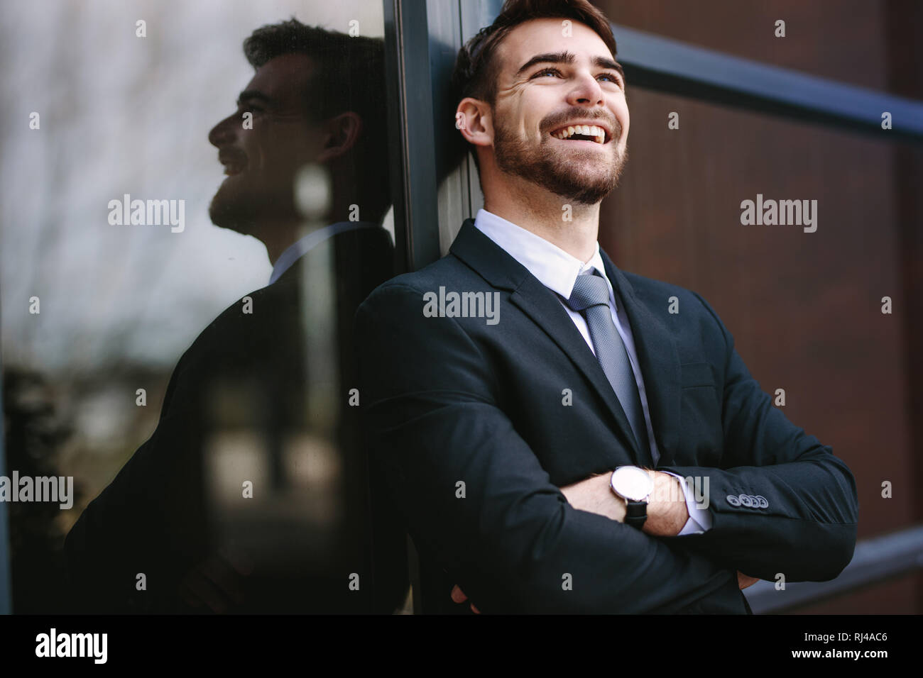 Cheerful businessman standing with his arms crossed looking away and ...