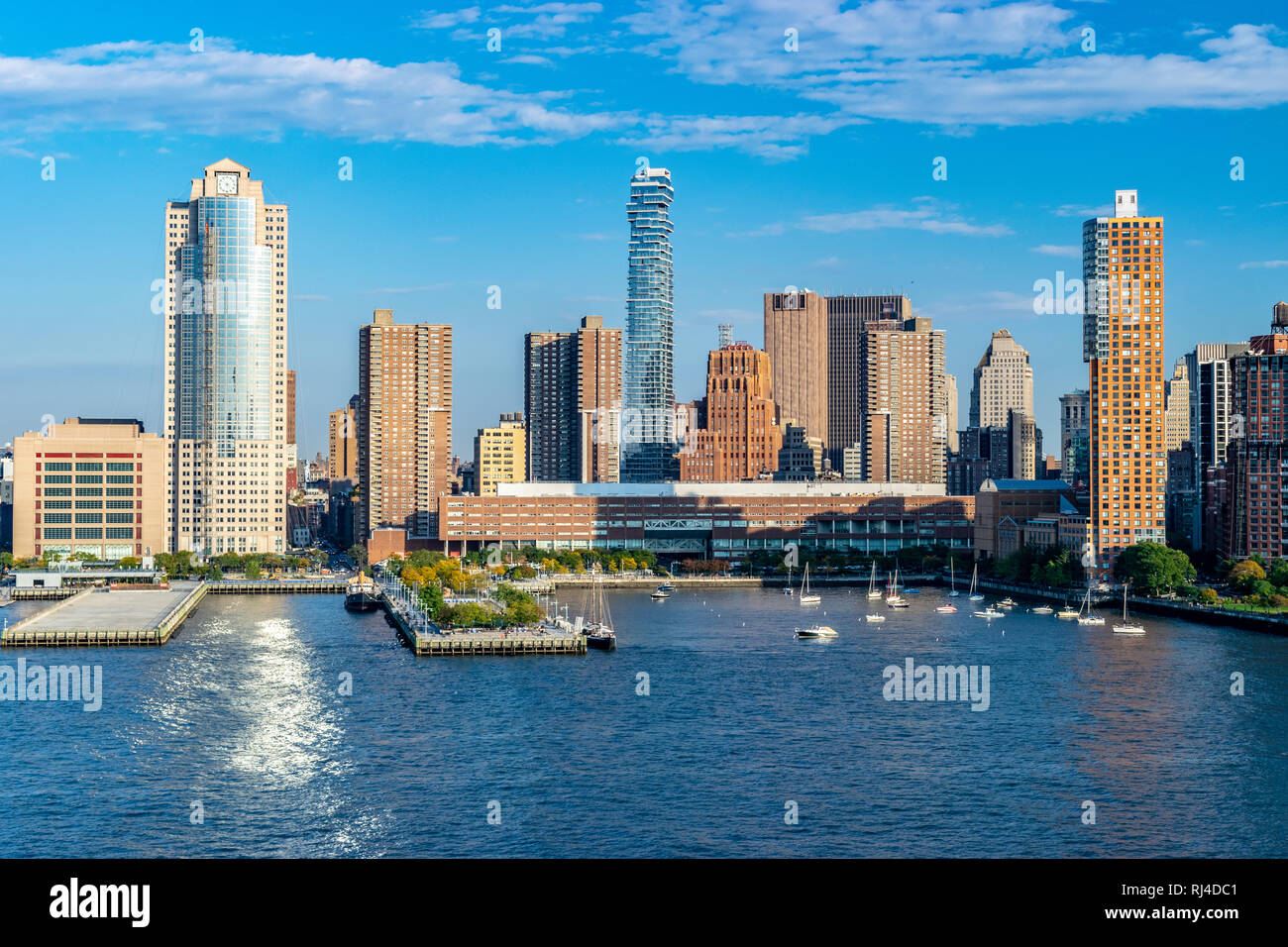 Lower Manhattan skyline in New York City from the Hudson River on a sunny Autumn evening with boats and yachts in the harbor. Stock Photo