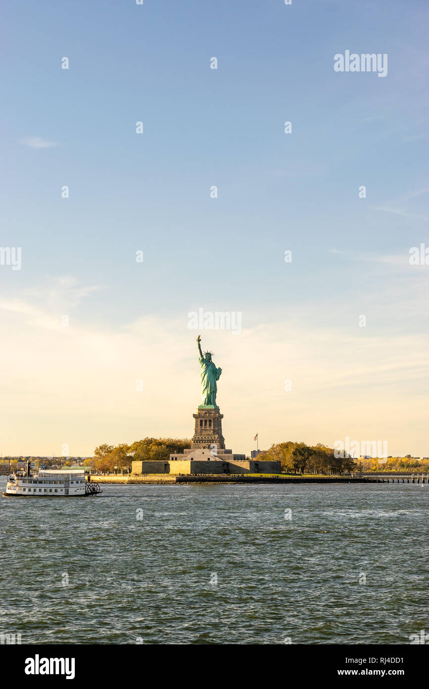 The Statue of Liberty in New York City with tour boat sailing by. Vertical. Copy Space for text. Stock Photo