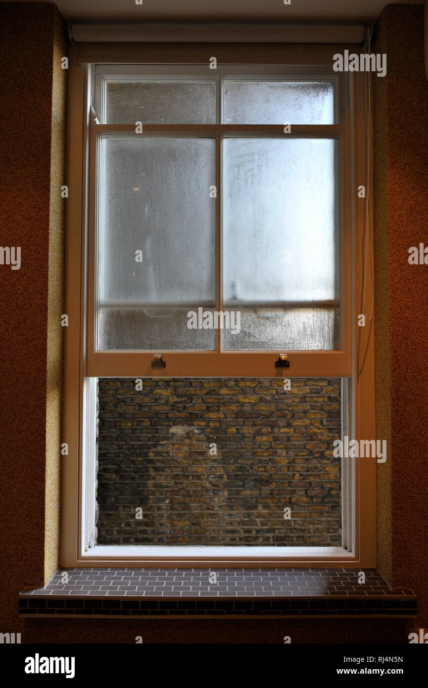 geöffnetes Fenster zum Hinterhof mit Blick auf eine Backsteinmauer in London Stock Photo