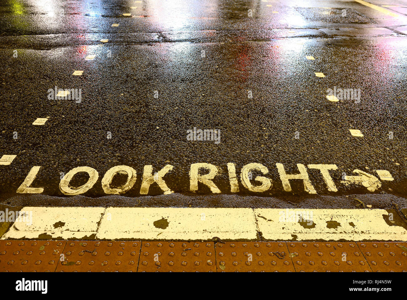 Straßenmarkierung auf einer regennassen Strasse, look right Stock Photo