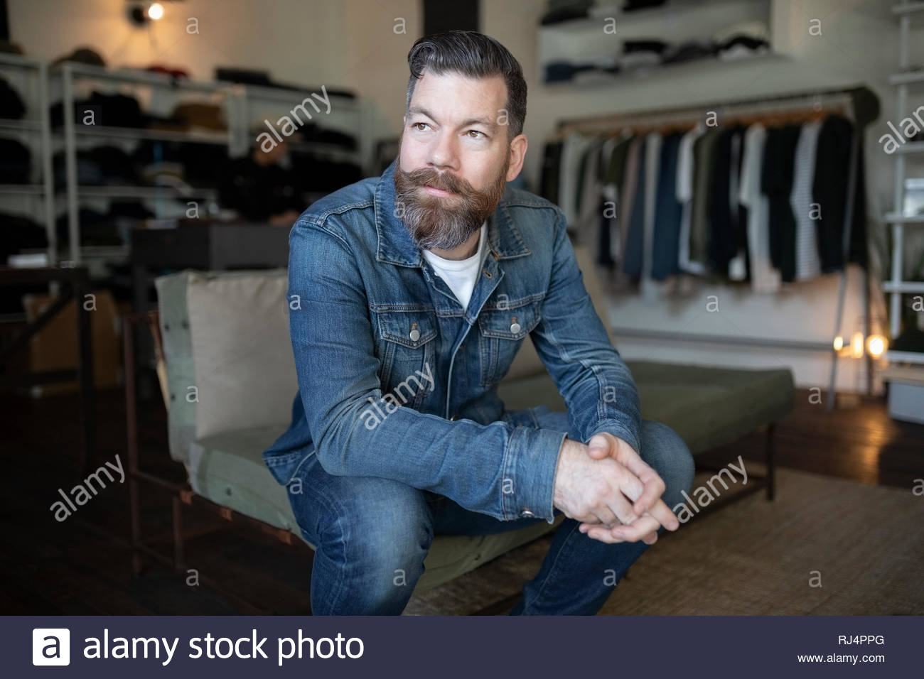 Confident male business owner sitting in menswear clothing shop Stock Photo