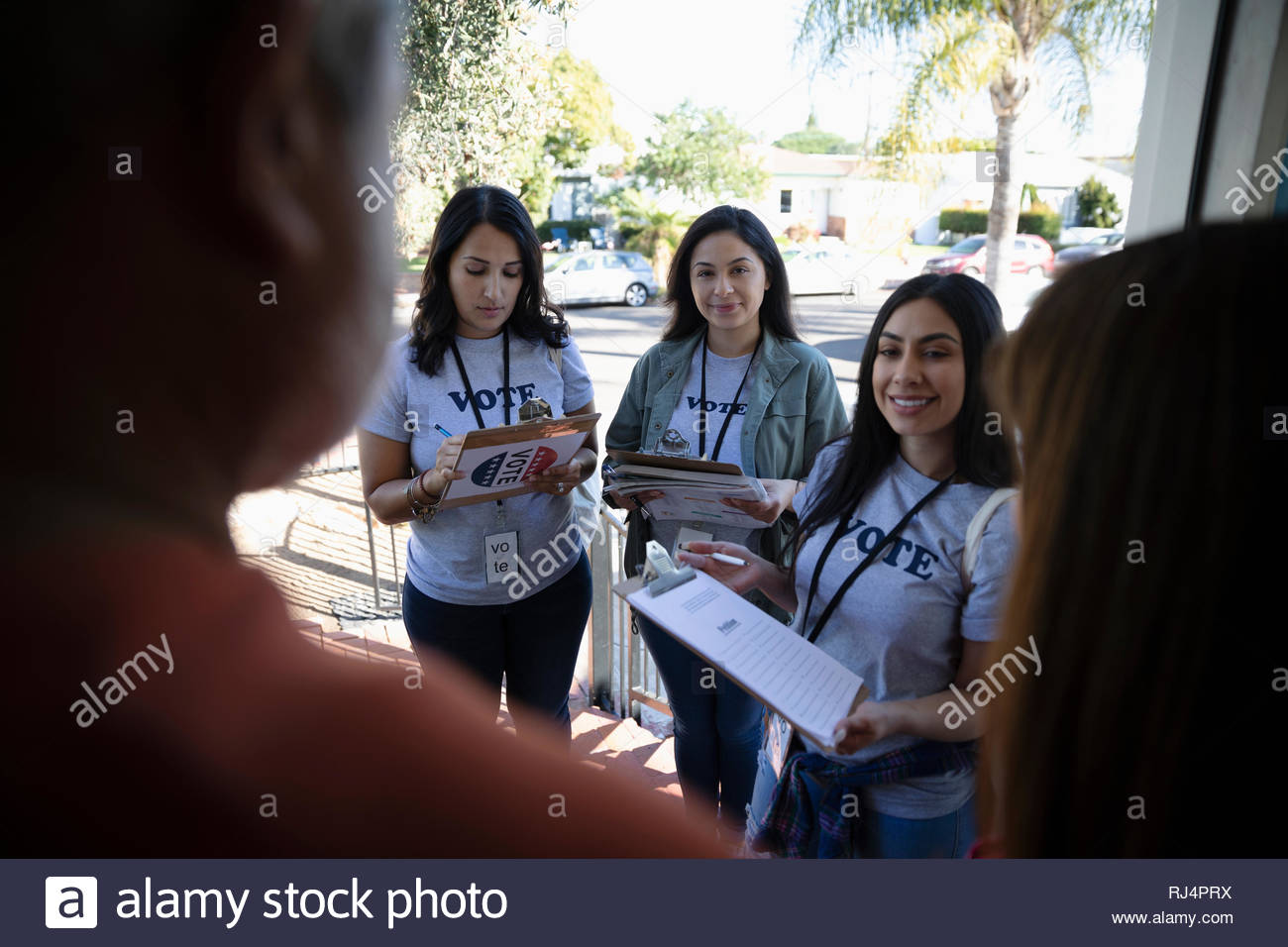 Latinx Female Volunteers Canvassing Voters Door To Door Stock
