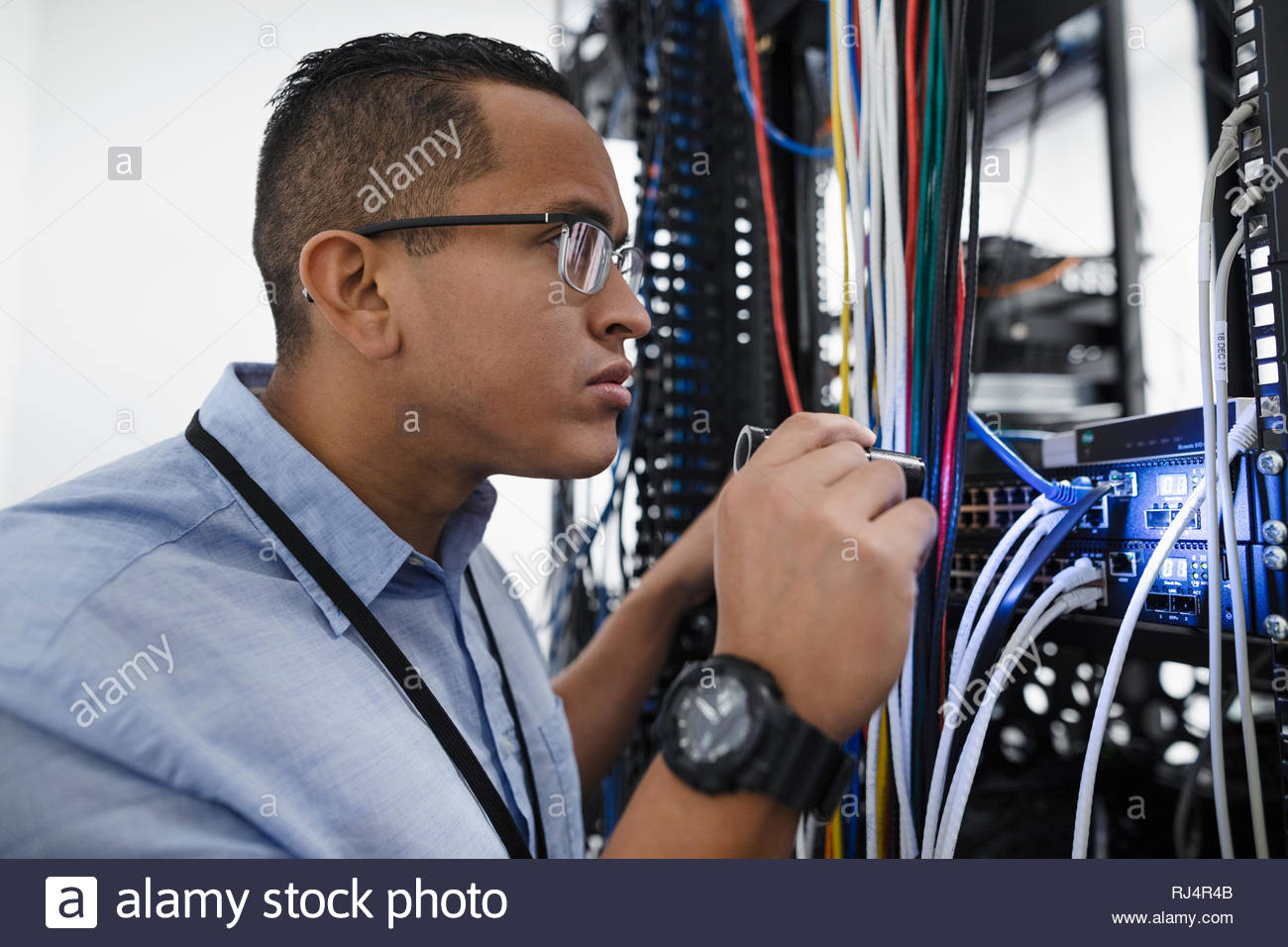 Focused IT technician examining connection plugs in server room Stock