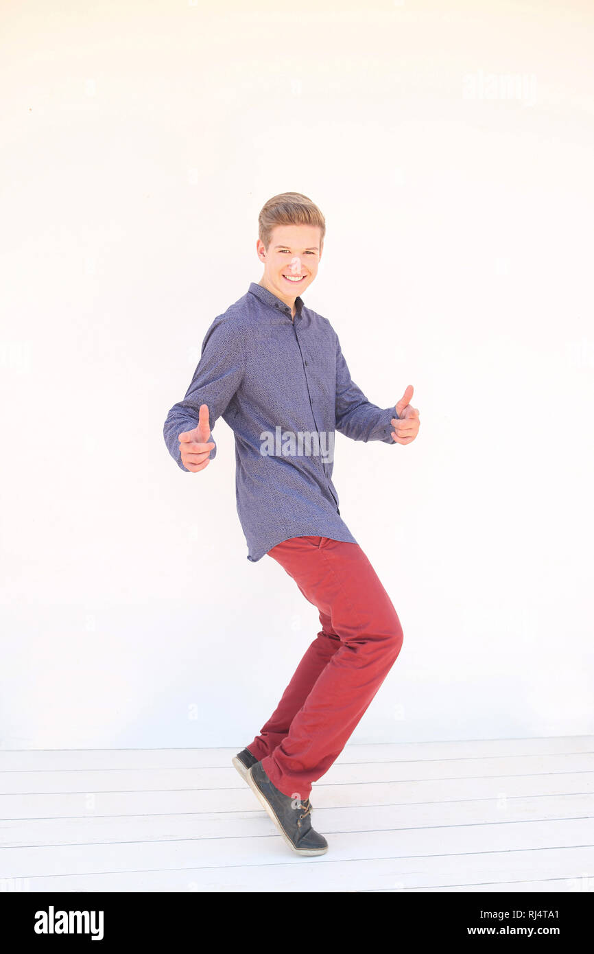 Jugendlicher mit blauem Hemd und roter Hose vor wei?em Hintergrund, Gestik, Pose, fr?hlich, lachen, Stock Photo