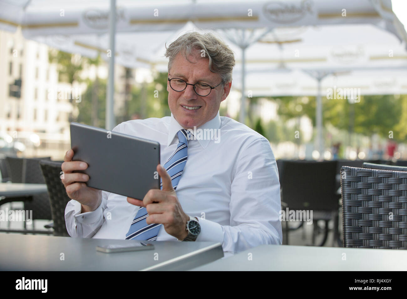 Geschäftsmann mit iPad sitzt am Tisch in Straßenrestaurant Stock Photo