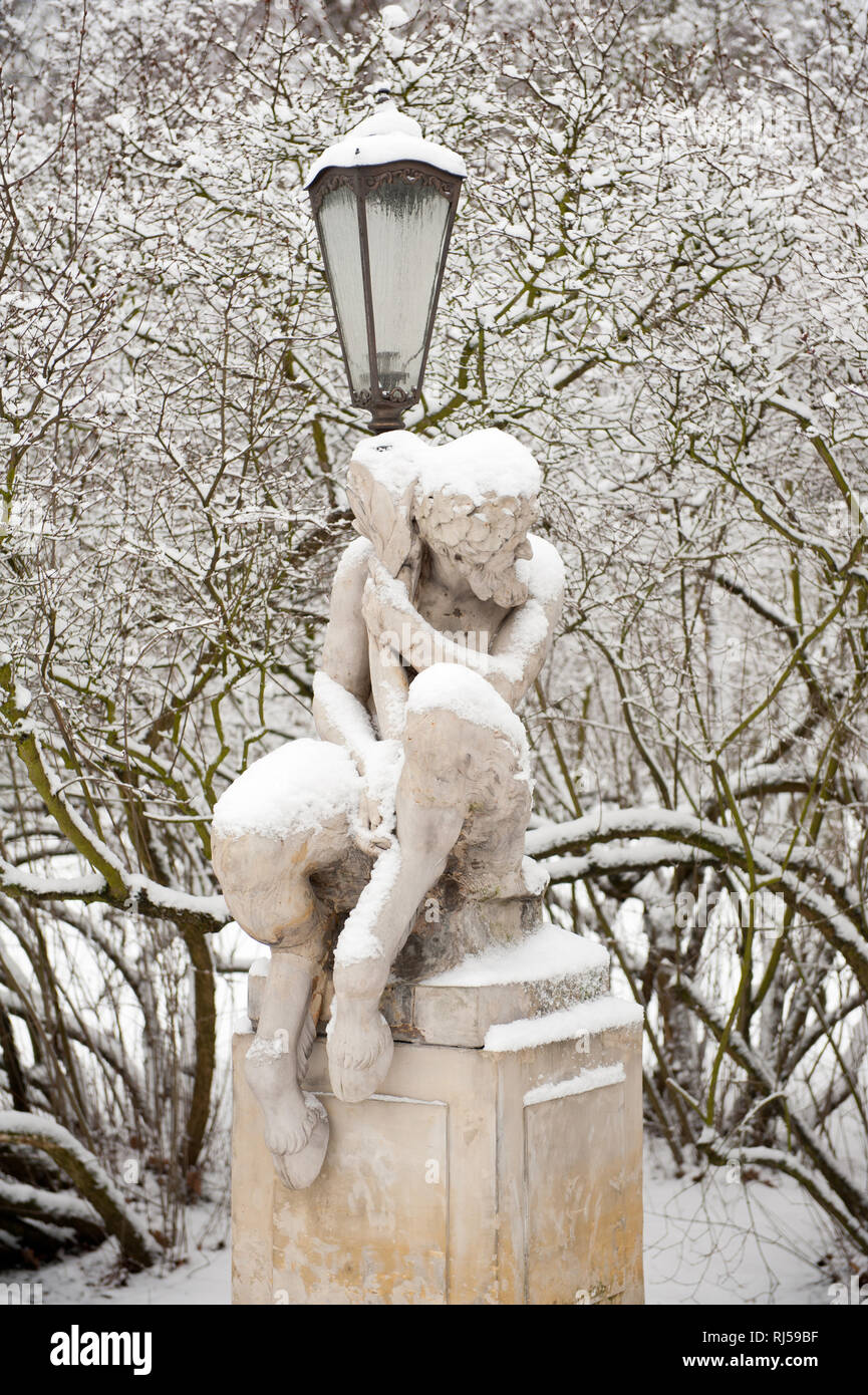 Satyr with decorative lamp statue in snow in Royal Baths Park in Warsaw, snowy weather in Polish Lazienki Krolewskie, Poland, Europe, Stock Photo