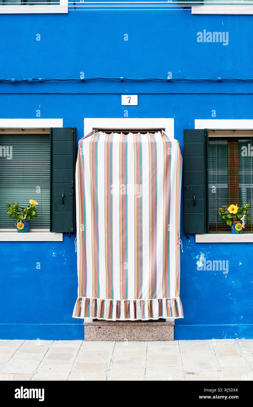 mit Stoff verhangene Haustüre, blaue Hausfassade in Burano Stock Photo