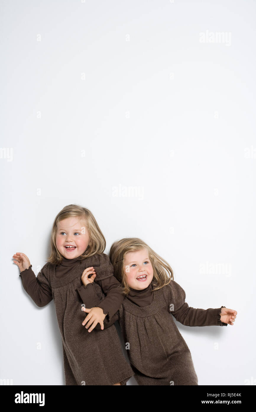Zwillingsmädchen toben vor weißer Wand Stock Photo