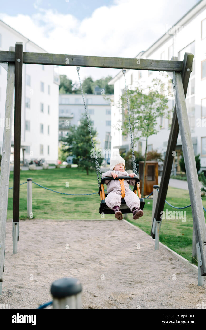 Girl having fun on swing in playground Stock Photo