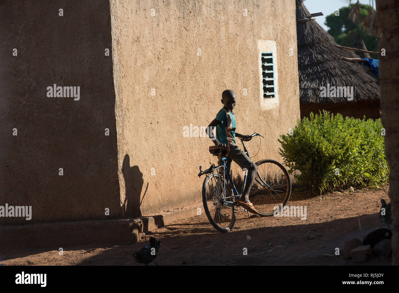 Bodadiougou village, Banfora, Cascades Region, Burkina Faso, 4th December 2016; A boy on his bike cycling through the village. Stock Photo