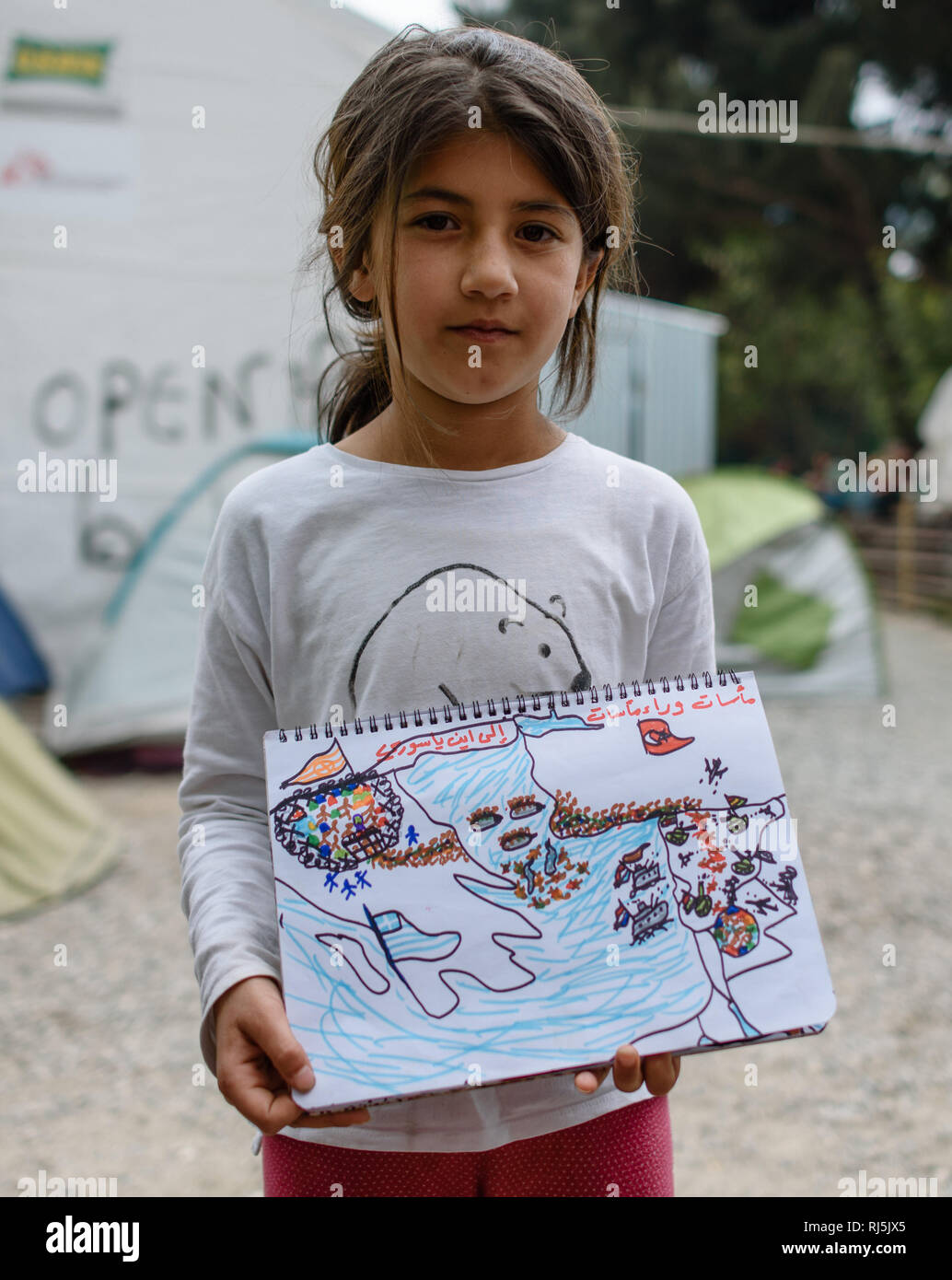 Dieses kurdische Mädchen will mir ihre tragische Geschichte anhand von Skizzen erzählen. Flüchtlingscamp von Idomeni in Griechenland an der Grenze nac Stock Photo