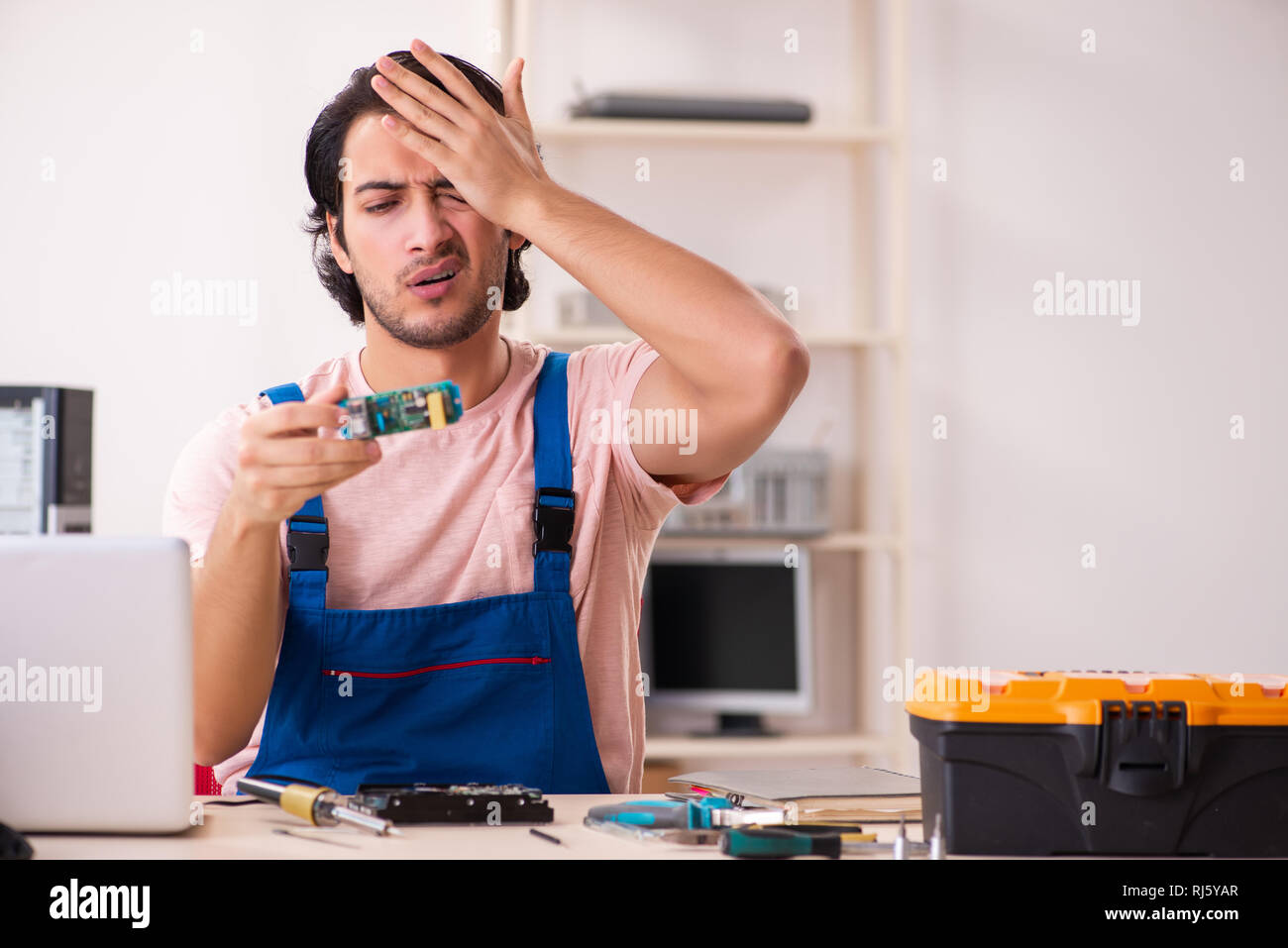 Young male contractor repairing computer Stock Photo