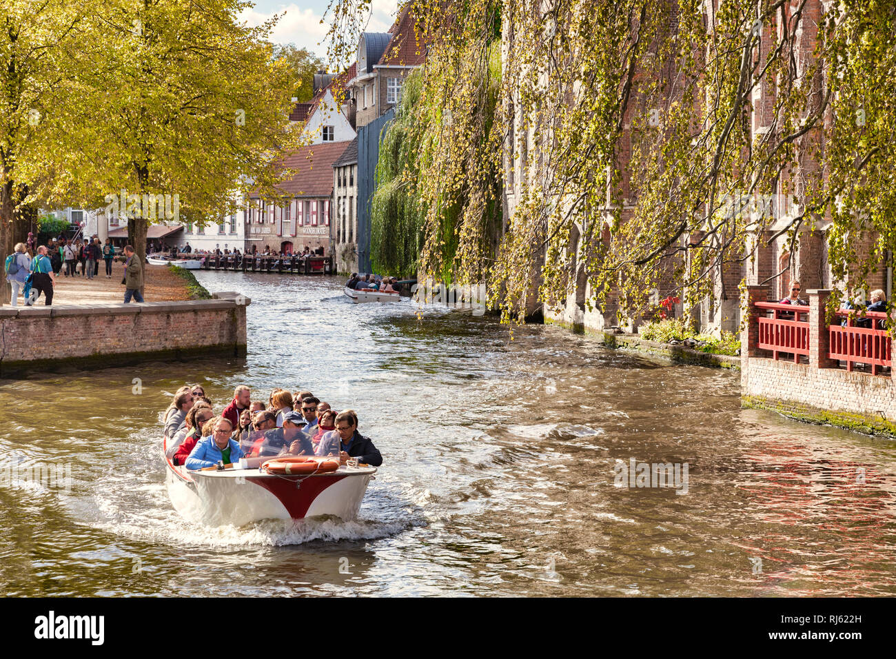 25 September 2018: Bruges, Belgium - Sightseeing boat on the Bruges canal on a sunny autumn day, trees turning to autumn colours. Stock Photo