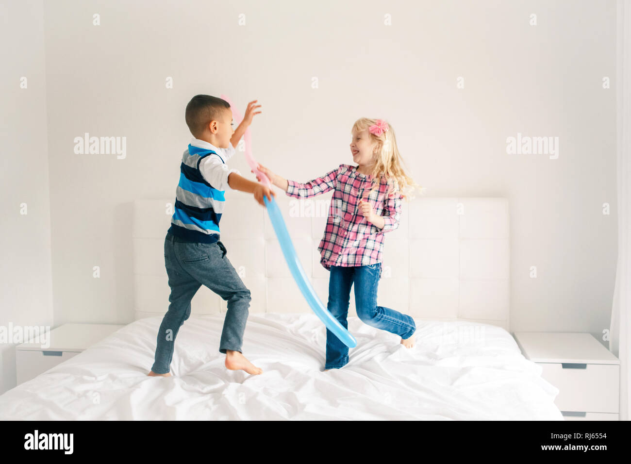 Two Caucasian Cute Adorable Funny Children Jumping On Bed In Bedroom And Playing Boy And Girl Are Having Fun Fighting With Balloons Best Friends For Stock Photo Alamy