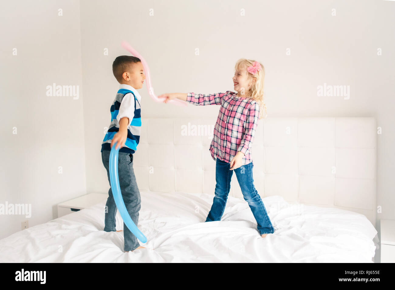Two Caucasian Cute Adorable Funny Children Jumping On Bed In Bedroom And Playing Boy And Girl Are Having Fun Fighting With Balloons Best Friends For Stock Photo Alamy
