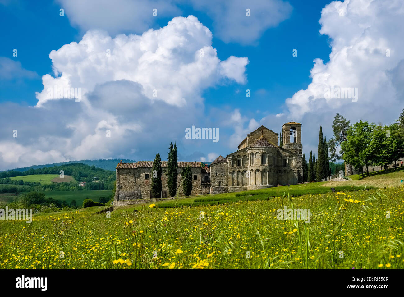 Typical hilly Tuscan countryside with fields, cypresses and the church Pieve di San Pietro a Romena Stock Photo