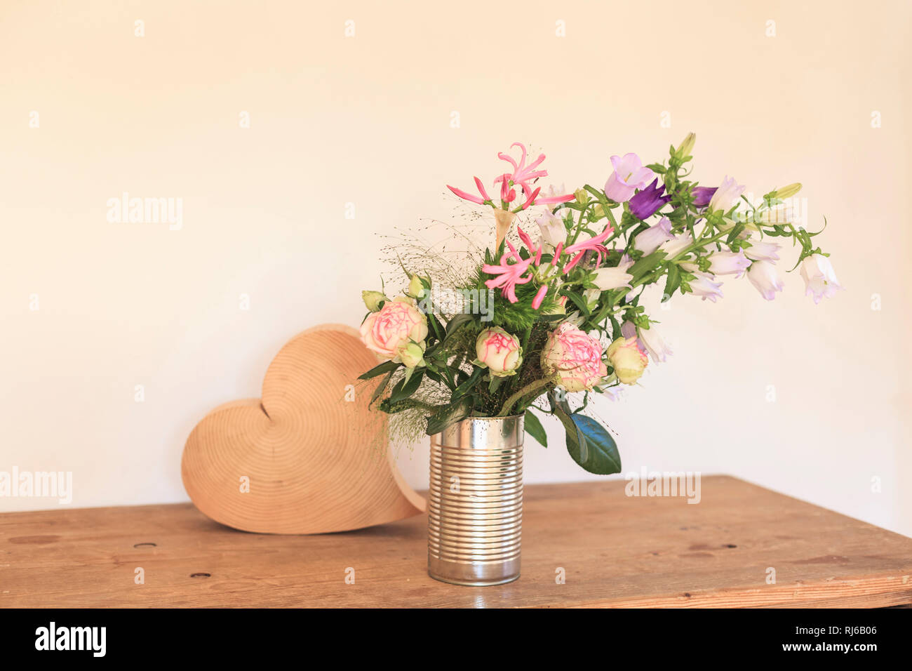 Strauß Sommerblumen, Dose als Vase, daneben ein Herz aus Holz Stock Photo