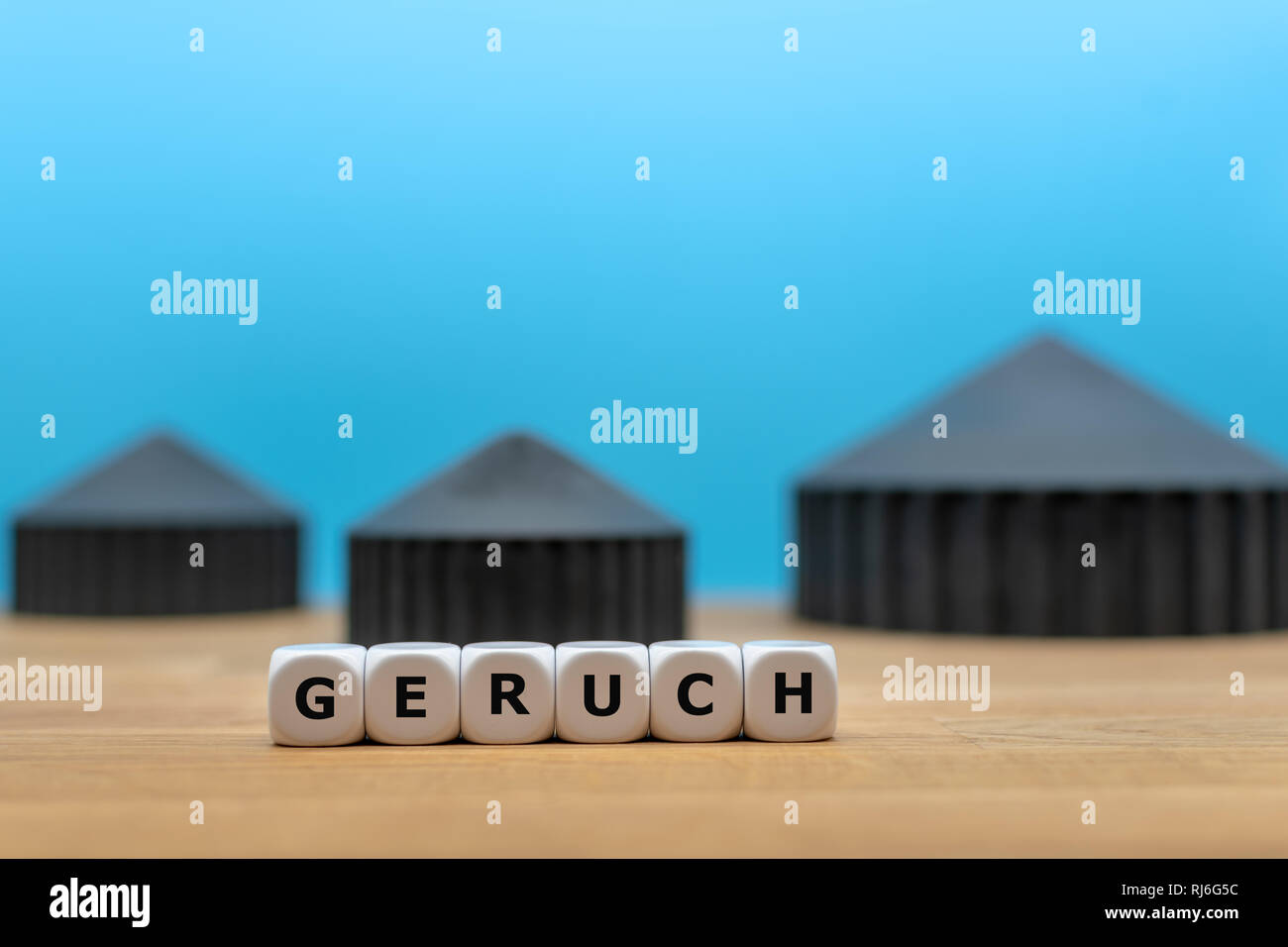 Dice form the German word 'GERUCH' ('smell' in English) in front of a model of a bio-gas plant. Stock Photo