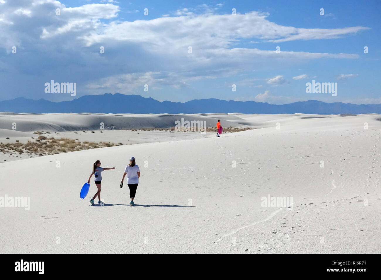 Kids look for a place to go sledding on the sand in White Sands, New Mexico. A must stop tourist attraction and National Monument. Stock Photo