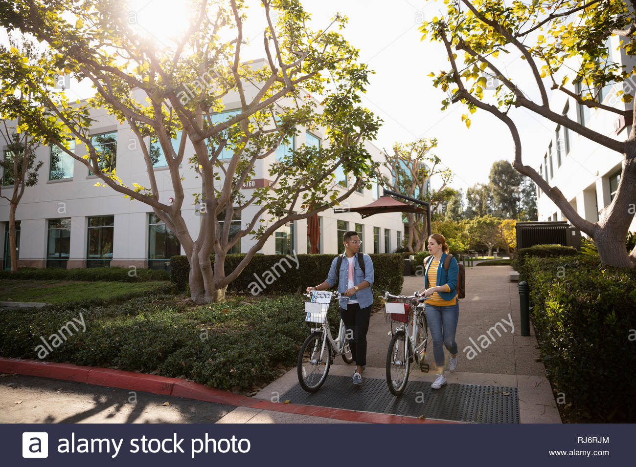 Man and woman walking bicycles in business park Stock Photo