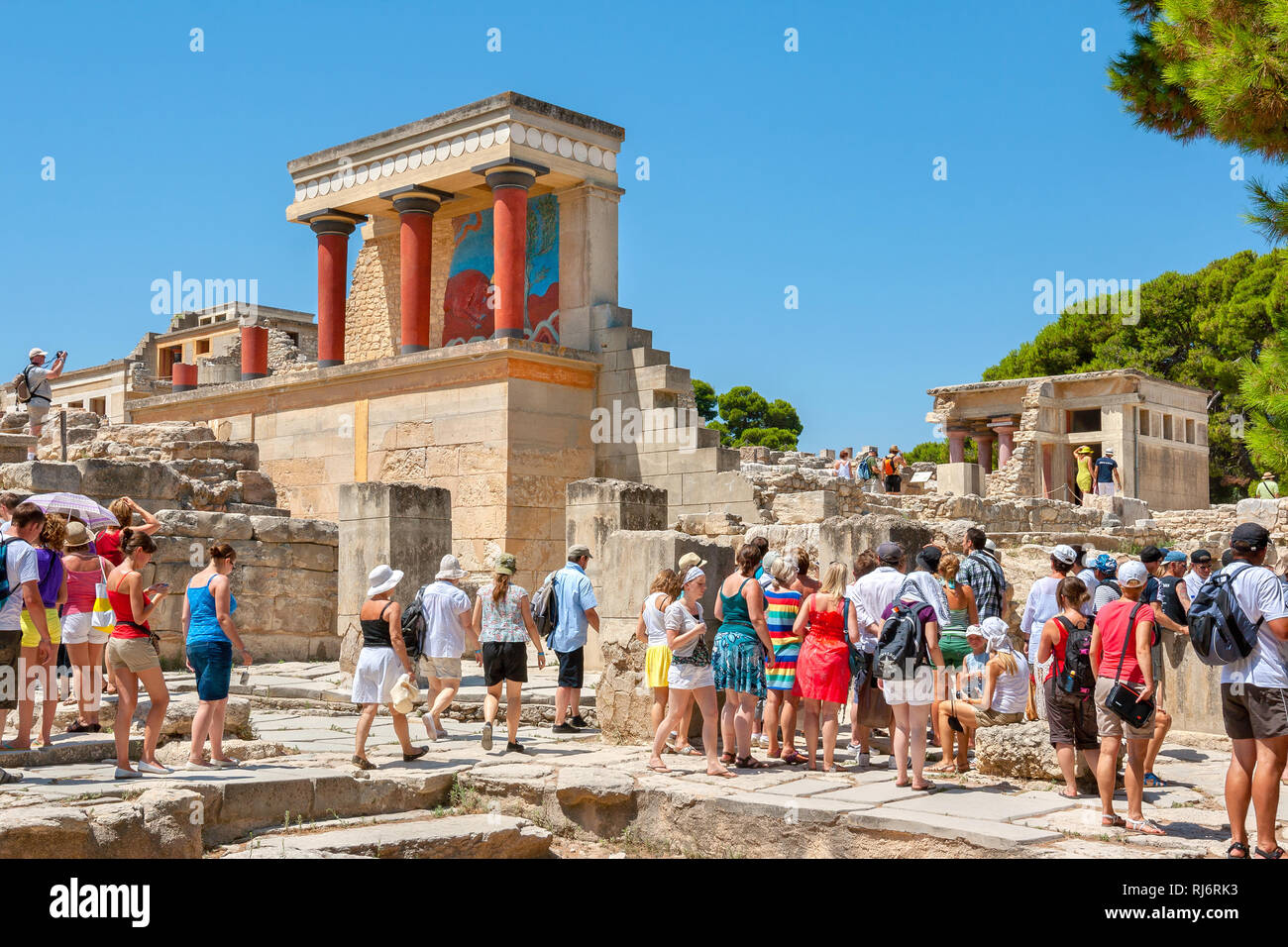 Tourist group on a guided tour in Knossos palace near restored North Entrance with charging bull fresco. Heraklion, Crete, Greeece Stock Photo