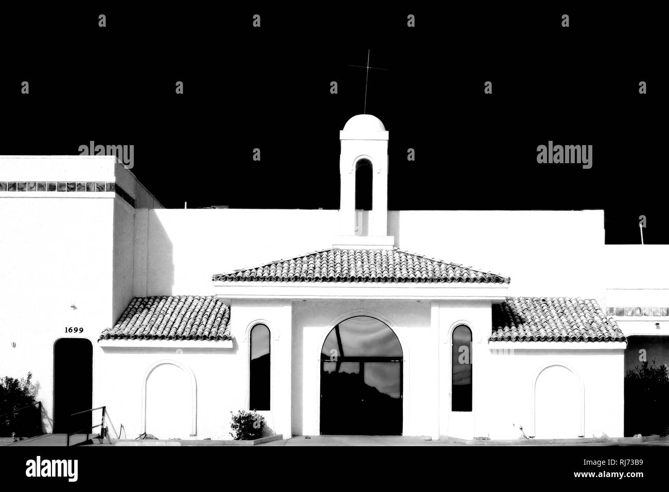 Eine Kirche im spanischen Stil mit weißen Wänden und schlichter Bauweise im Kontrast zur Dunkelheit, Stock Photo