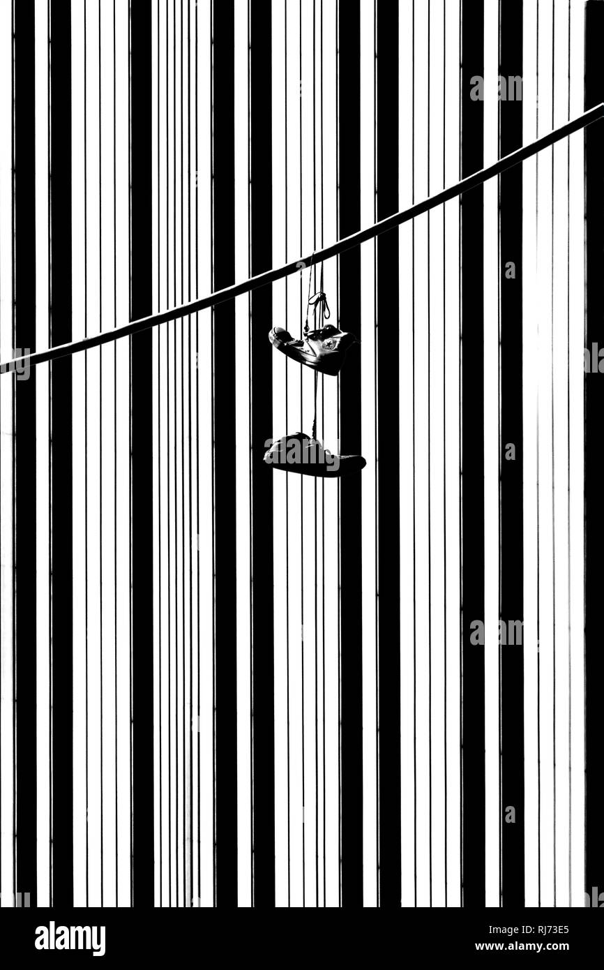 Abstrakte schwarz-weiß Fotografie der Fassade eines Hochhauses, Turnschuhe über einem Kabel, Stock Photo