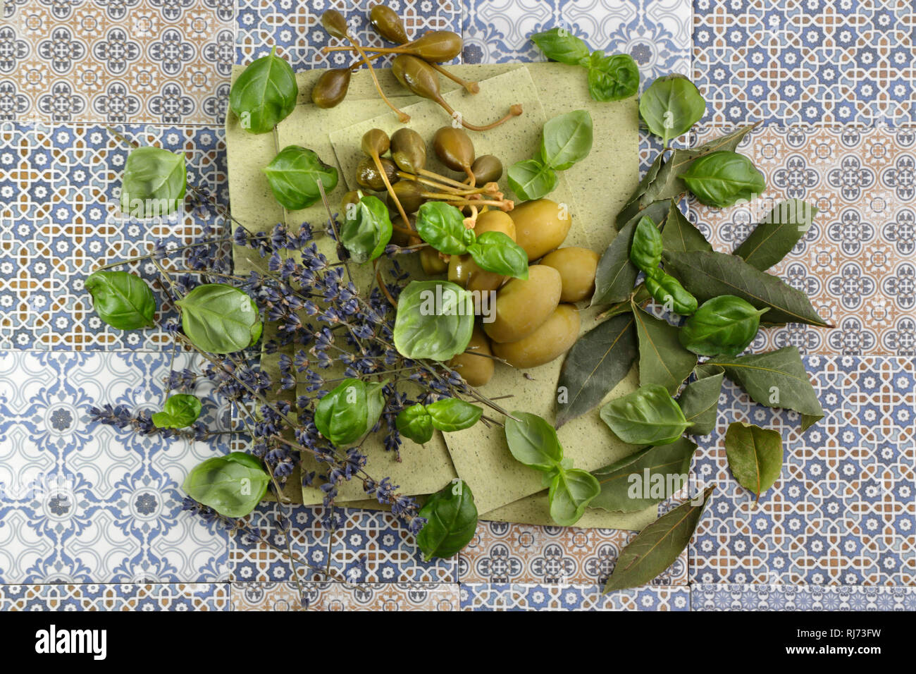 Oliven, Kapern und mediterranen Kräutern auf grünen Lasagneblättern Stock Photo