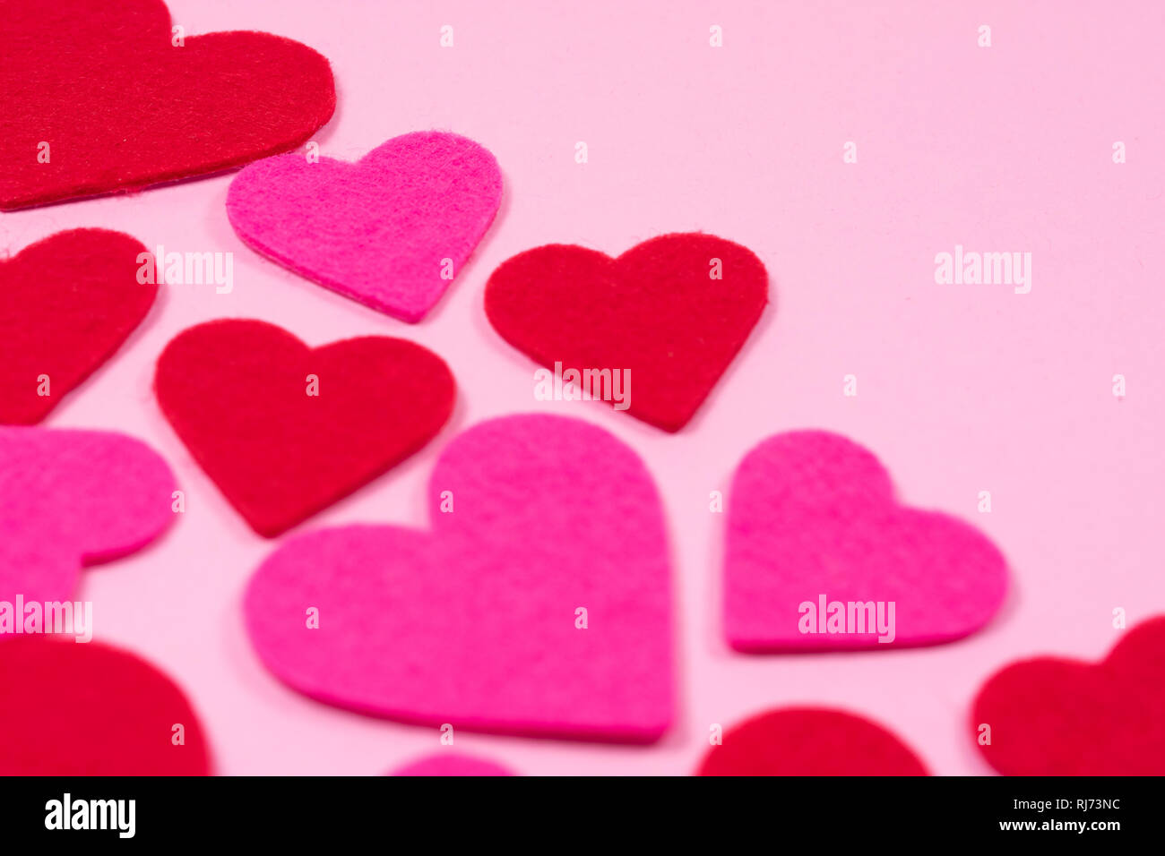 White Saint Valentine's day background with red and pink hearts, blurred focus, close-up view, copy space. Symbol of love, Love concept. Stock Photo