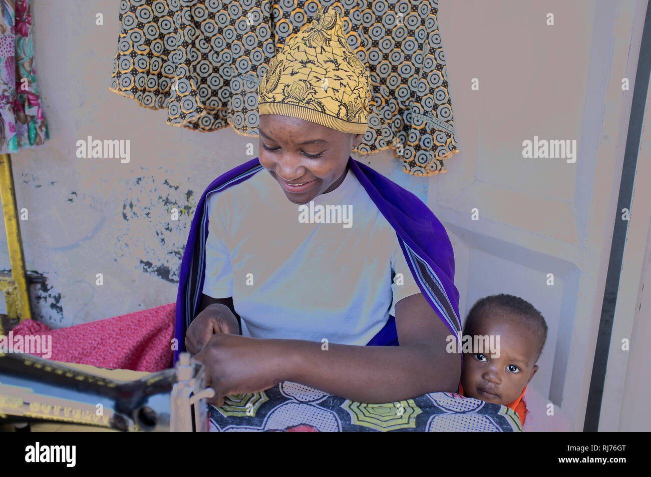 afrikanische Frau mit ihrem Baby an der Nähmaschine Stock Photo